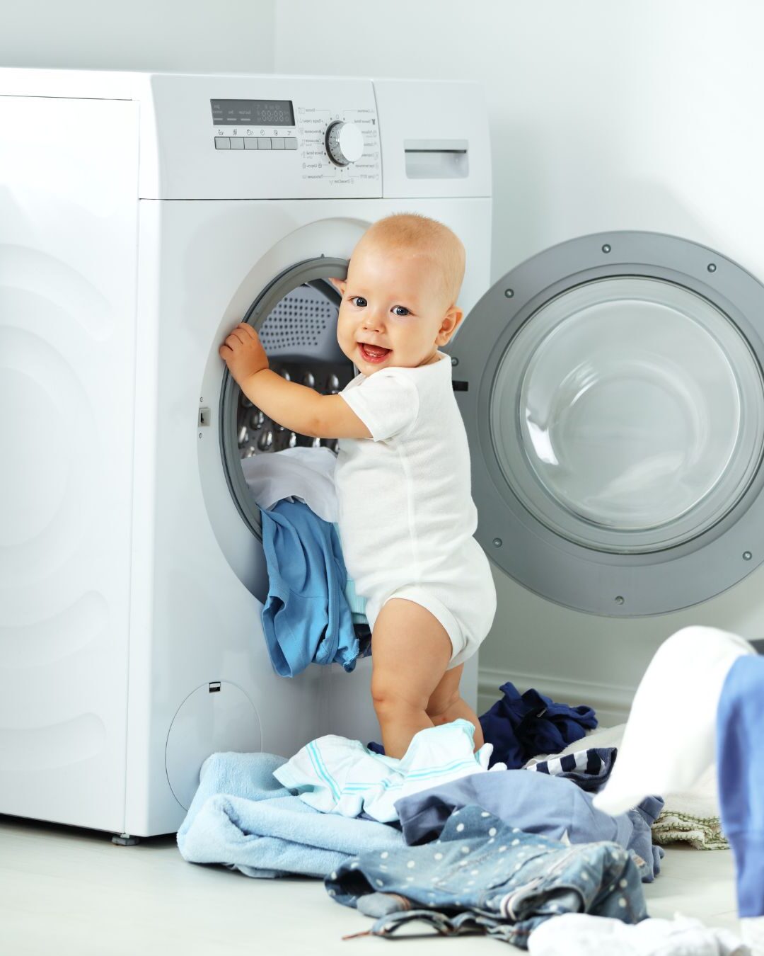 baba teszi a babaruhát a mosógépbe